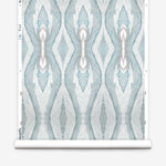 Wallpaper roll in a watercolor diamond print in shades of gray and blue on a cream field.