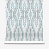 Wallpaper roll in a watercolor diamond print in shades of gray and blue on a cream field.