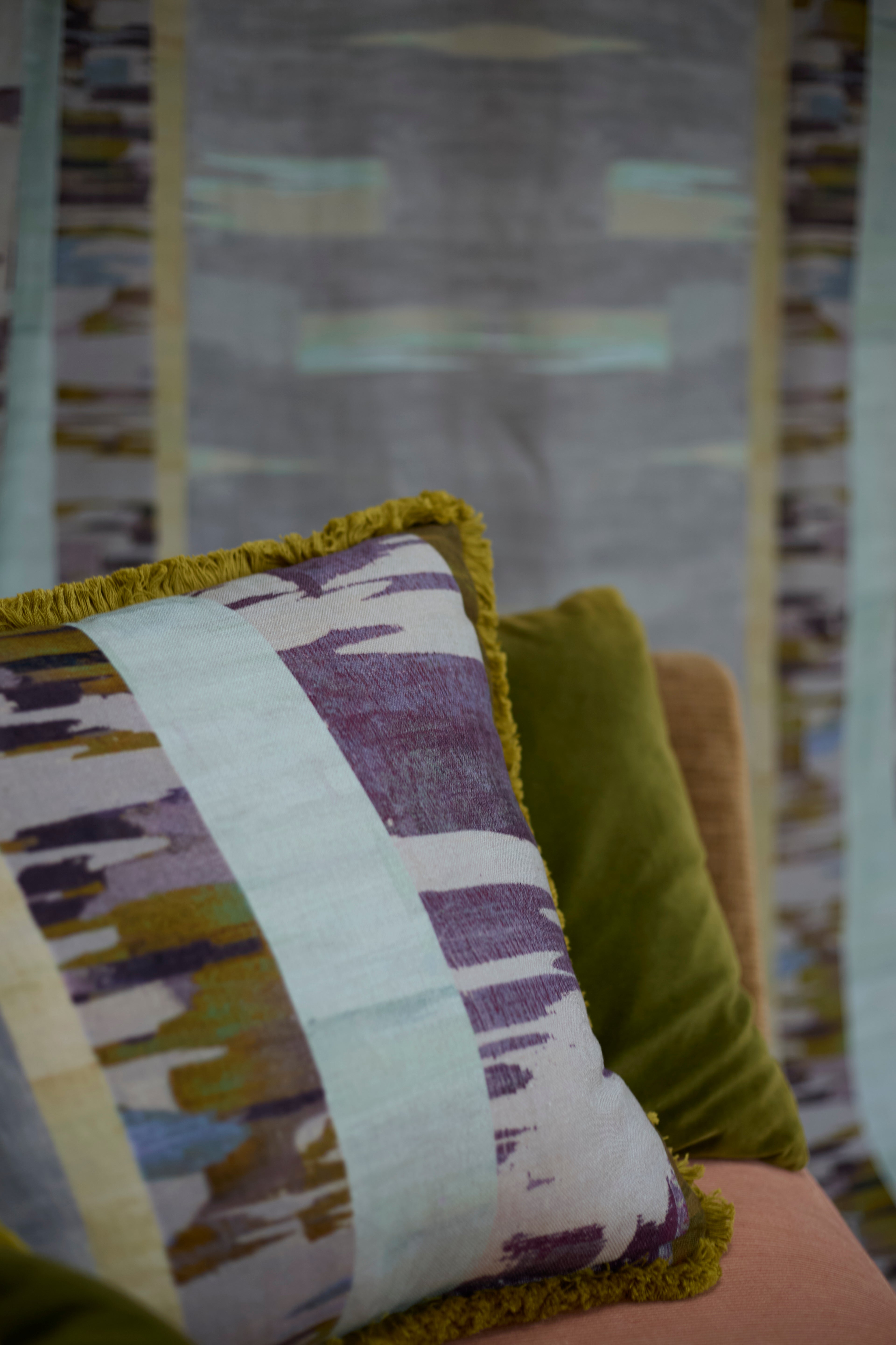 Decorative pillow with fringe in a watercolors stripe design.