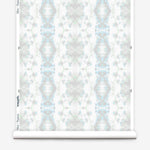 Partially unrolled wallpaper yardage in a painterly gometric stripe in gray, blue and green on a white field.