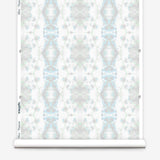 Partially unrolled wallpaper yardage in a painterly gometric stripe in gray, blue and green on a white field.