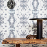 A wooden table with a snake on it stands in front of a wall papered in a painterly gometric stripe in gray, blue and cream.