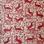 Detail of wallpaper in a deer, leaf and flower print in red on a mottled beige field.