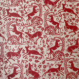 Detail of wallpaper in a deer, leaf and flower print in red on a mottled beige field.