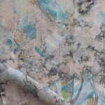 Detail of fabric in a painterly tree print in cream, gray and turquoise.