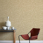 Modern interior with a red chair, table, and decorative items against a leaf patterned wall.