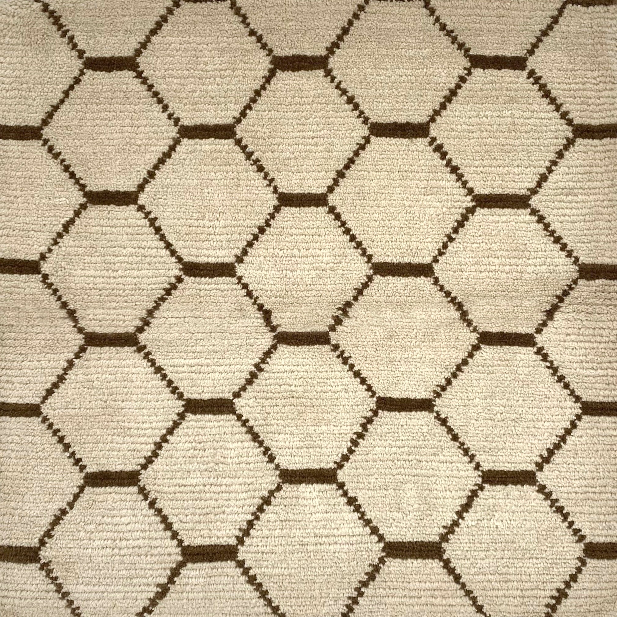 Handknotted Moroccan style rug with a brown lattice on a cream field.