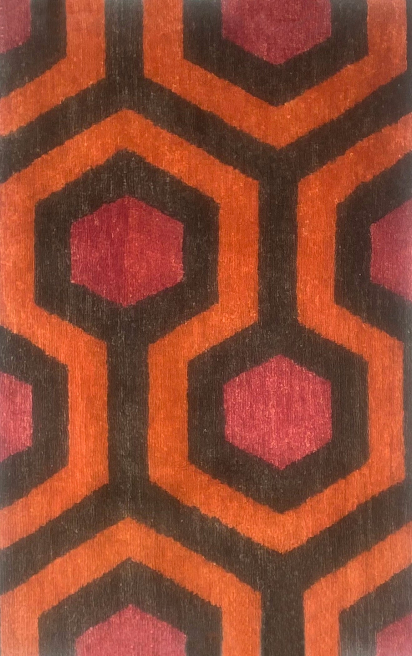 Handknotted rug sample in a retro hexagon design in red, brown and orange.