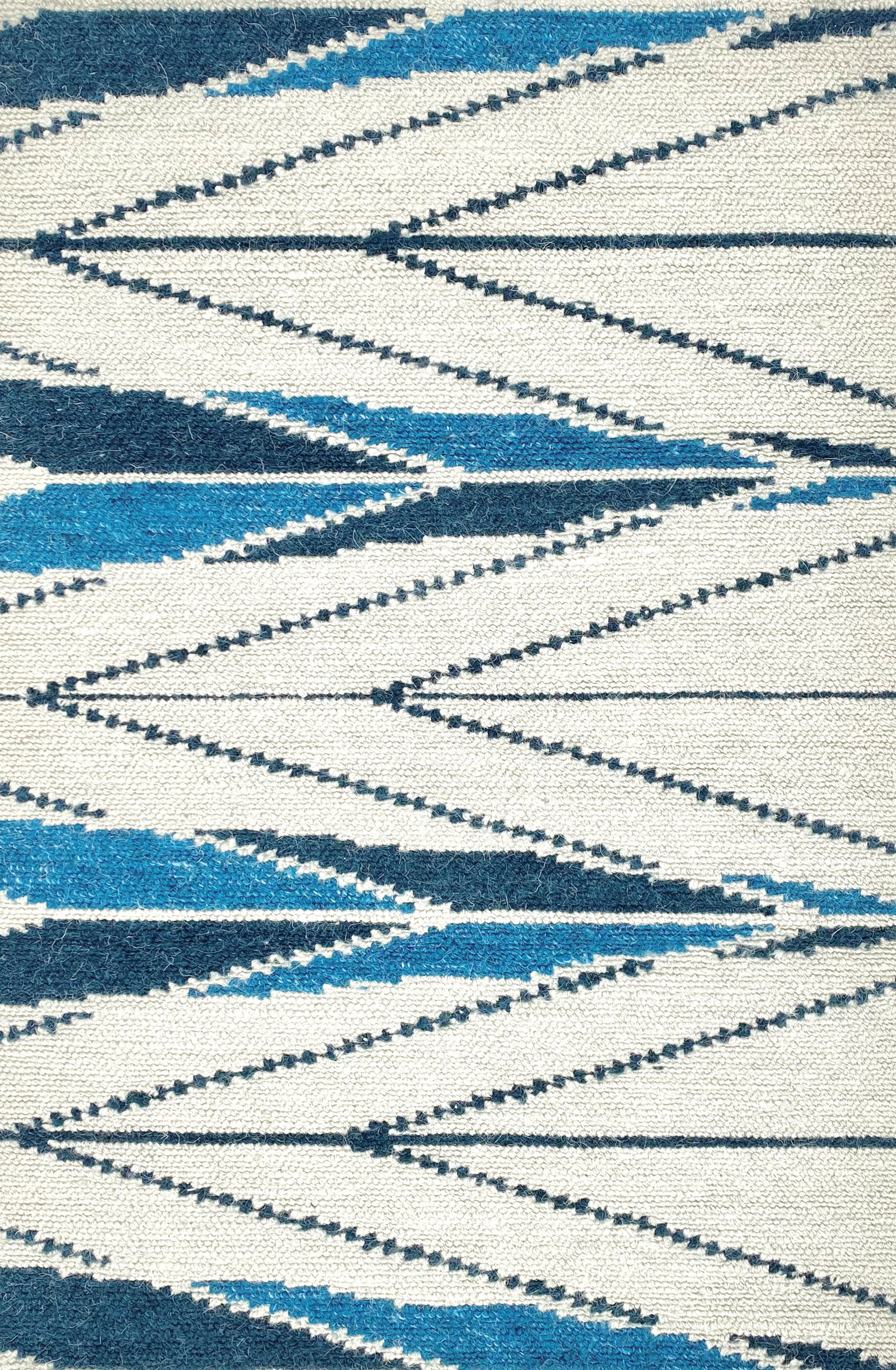 Handknotted rug sample in a modern herringbone design in shades of blue ona. white field. 