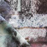 Detail of fabric in a minimal splatter print in shades of green, brown and pink on a cream field.