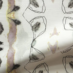 Detail of draped fabric yardage in a watercolor ikat stripe print in shades of gray, pink and yellow on a white field.