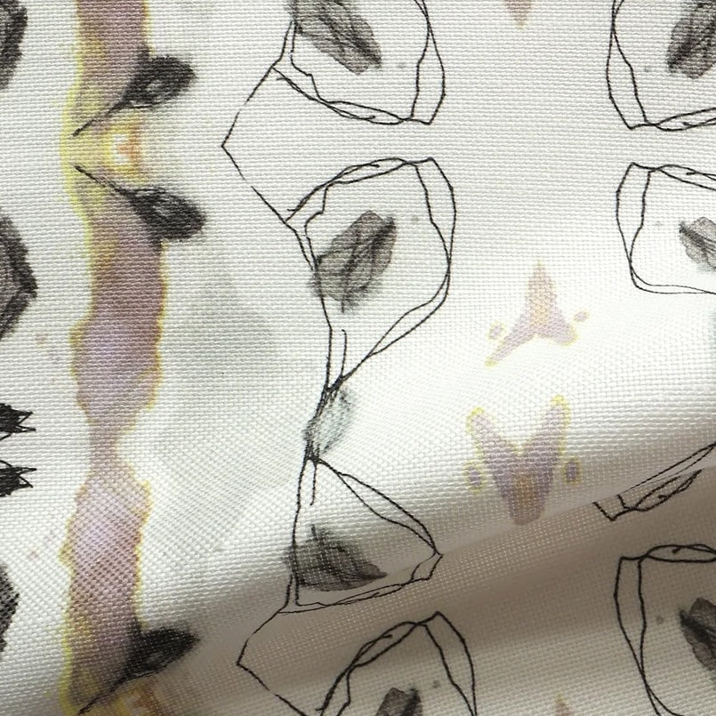 Detail of draped fabric yardage in a watercolor ikat stripe print in shades of gray, pink and yellow on a white field.