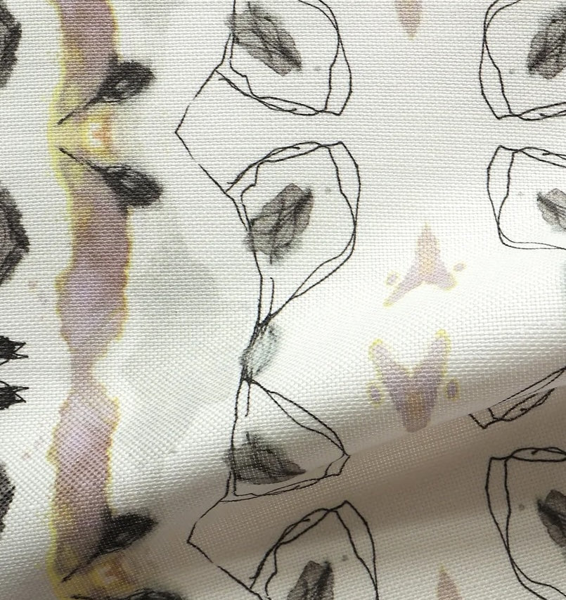 Detail of draped fabric yardage in a watercolor ikat stripe print in shades of gray, pink and yellow on a white field.