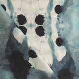 Close-up of draped fabric in a watercolor ink blot print in shades of charcoal and gray on a tan field.