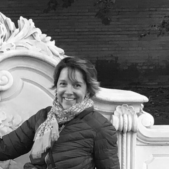 Black and white portrait of an older woman with short hair smiling and leaning against a carved marble surface.
