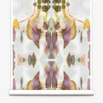 Partially unrolled wallpaper yardage in a watercolor paint blotch print in shades of gray, yellow and pink on a white field.