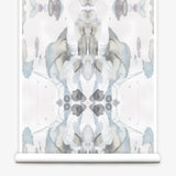 Partially unrolled wallpaper yardage in a watercolor paint blotch print in shades of gray and blue on a white field.