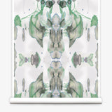 Partially unrolled wallpaper yardage in a watercolor paint blotch print in shades of gray and green on a white field.