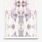 Partially unrolled wallpaper yardage in a watercolor paint blotch print in shades of gray and pink on a white field.