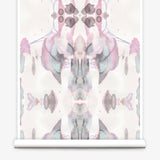 Partially unrolled wallpaper yardage in a watercolor paint blotch print in shades of gray and pink on a white field.