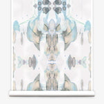 Partially unrolled wallpaper yardage in a watercolor paint blotch print in shades of gray, blue and tan on a white field.