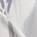 Draped fabric yardage in a watercolor paint print in shades of purple and gray on a cream field.