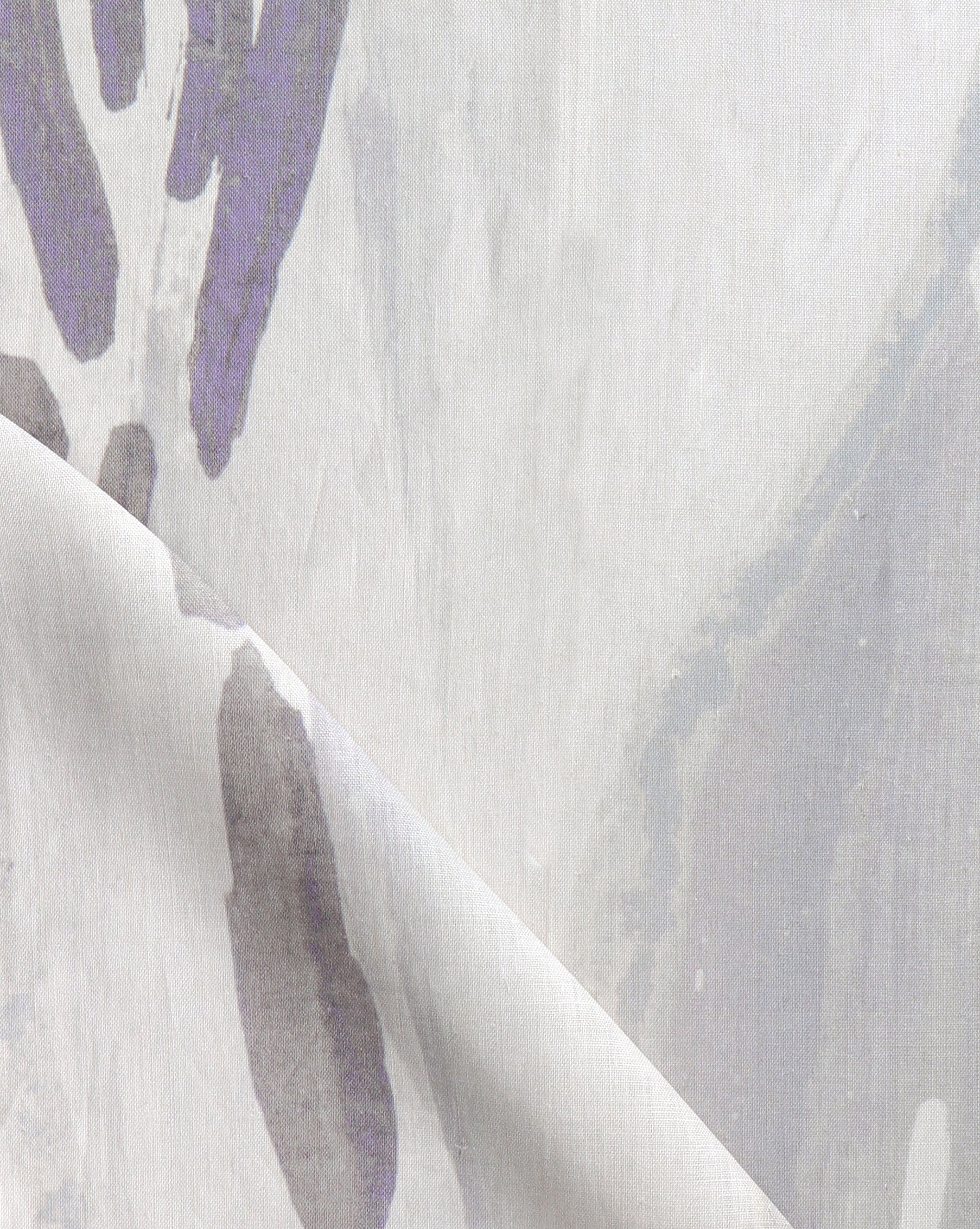 Draped fabric yardage in a watercolor paint print in shades of purple and gray on a cream field.