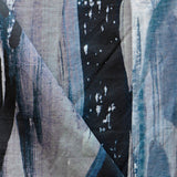 Draped fabric yardage in a watercolor paint print in shades of black, purple and blue on a gray field.
