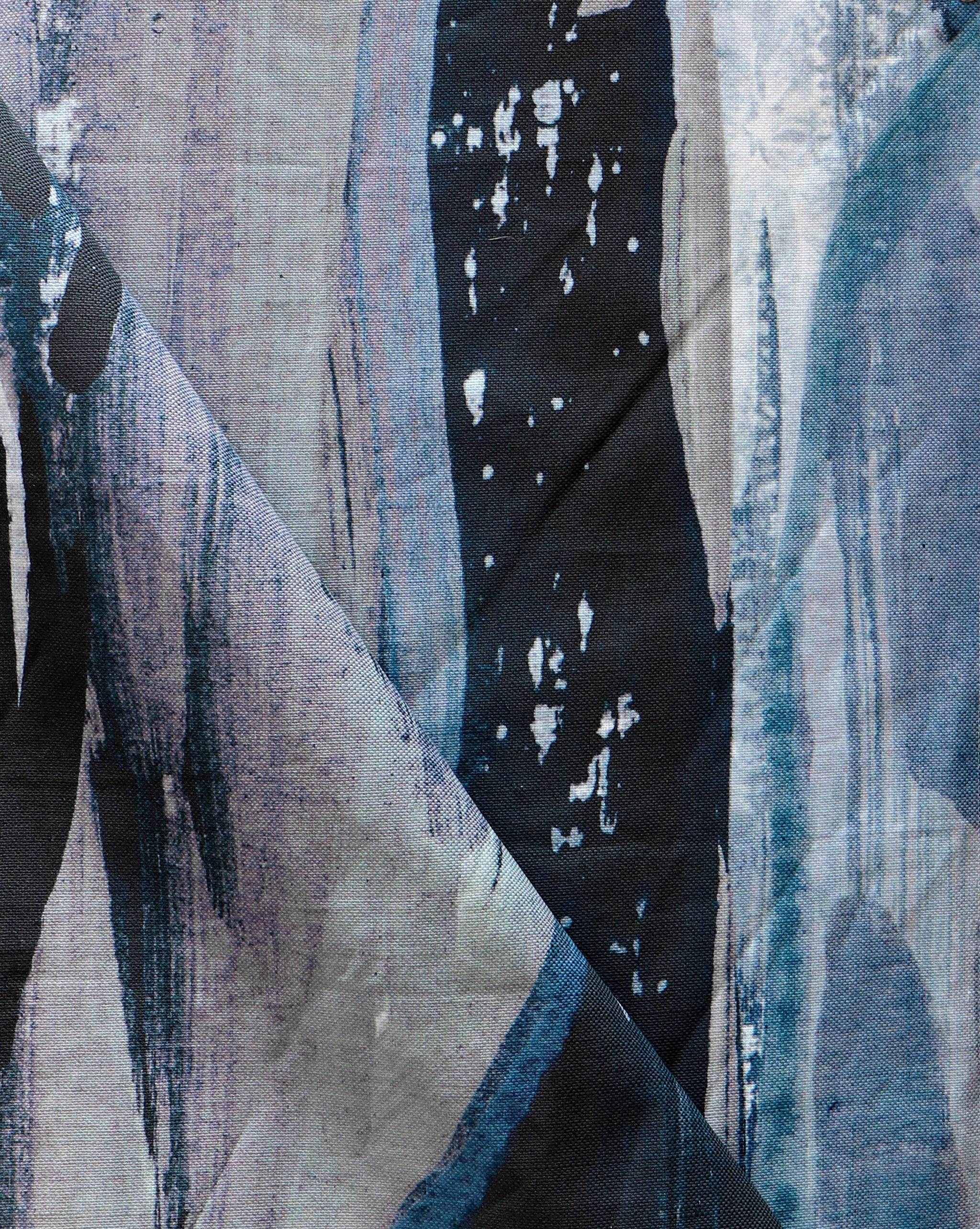 Draped fabric yardage in a watercolor paint print in shades of black, purple and blue on a gray field.
