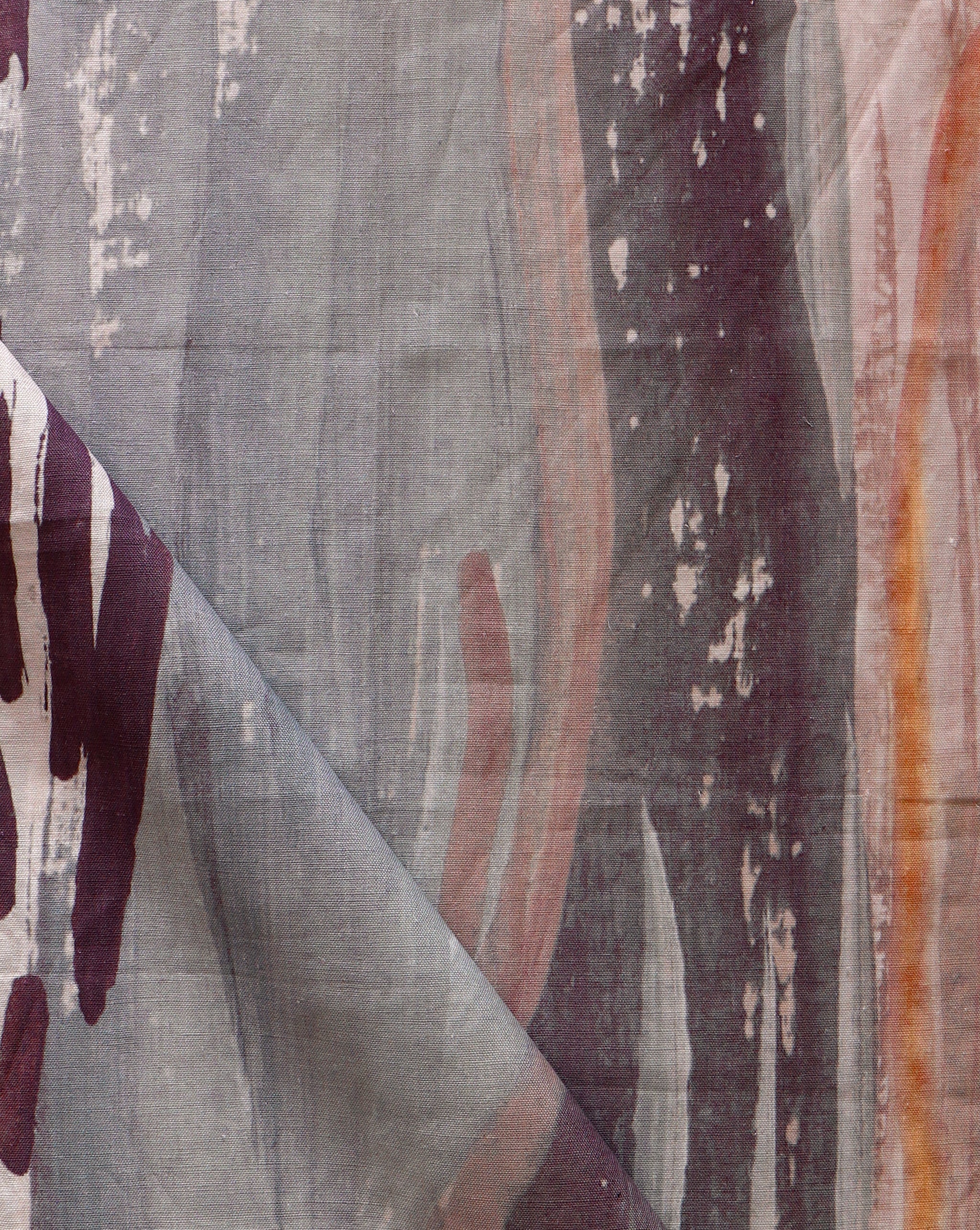 Draped fabric yardage in a watercolor paint print in shades of gray, orange and purple on a cream field.