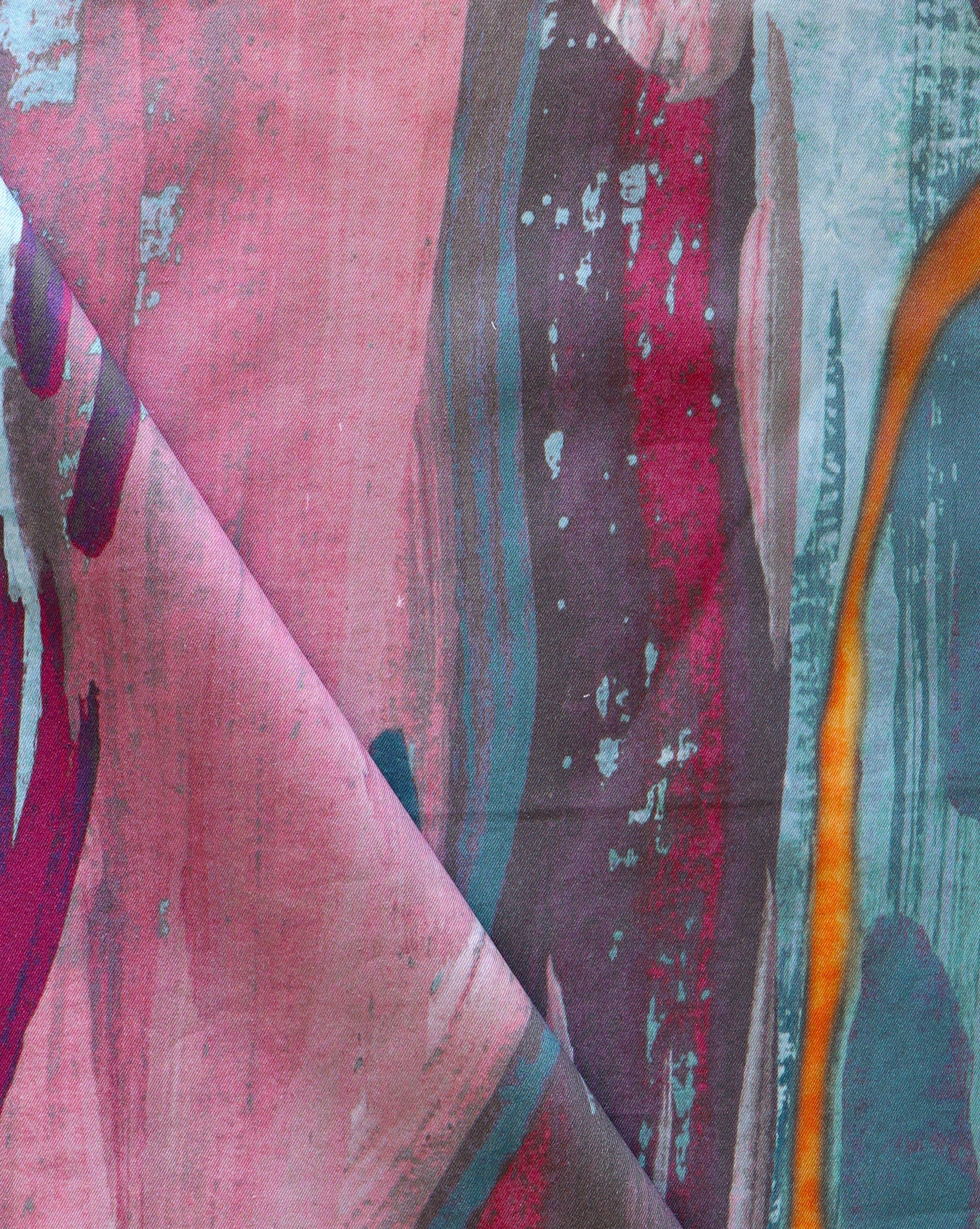 Draped fabric yardage in a watercolor paint print in shades of pink, purple and turquoise on a blue field.