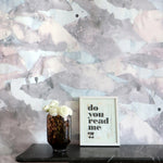 Decorative wall with abstract pattern, vase with flowers, and framed picture on a shelf.