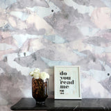 Decorative wall with abstract pattern, vase with flowers, and framed picture on a shelf.