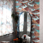 Room interior with abstract wallpaper in brown and teal, a mirror, and decorative elements.
