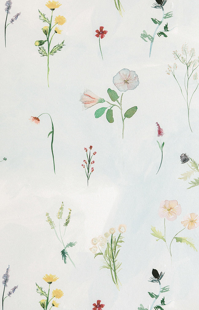 Detail of wallpaper in a painterly flower print in green and pastels on a cream field.