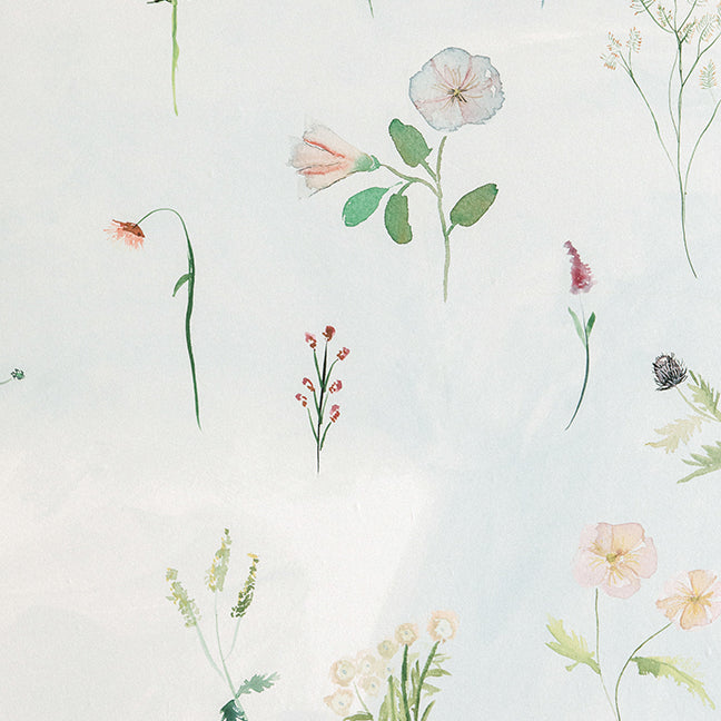 Detail of wallpaper in a painterly flower print in green and pastels on a cream field.