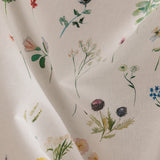 Draped fabric yardage in a painterly flower print in green and pastels on a cream field.