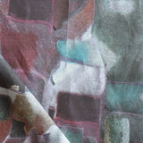 Draped fabric yardage in a textural paint blotch print in shades of purple, turquoise and green on a gray field.