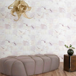 Modern beige ottoman in a room with watercolor check-patterned wallpaper and a decorative light fixture.