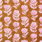 Detail of fabric in a classic floral print in bright pink and white on a rust orange field.