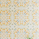 A potted plant stands in front of a wall covered in a painterly grid print in shades of blue and orange on a cream field.