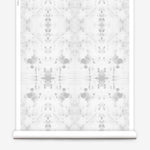 Partially unrolled wallpaper yardage in a watercolor ink blot print in gray on a white field.