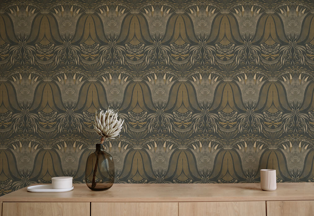 A table with a vase and cups stands in front of a wall papered in a floral damask print in cream, gold and navy.