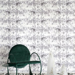 A modernist living tableau with a wall papered in a painterly palm tree stripe print in gray and white.