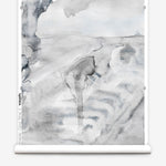 Partially unrolled wallpaper yardage in a watercolor painterly print in shades of gray and white.
