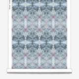Partially unrolled wallpaper yardage in a watercolor ink blot pattern in shades of gray, blue and pink.