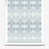 Partially unrolled wallpaper yardage in a watercolor ink blot pattern in shades of gray, green and pink.