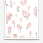 Partially unrolled wallpaper yardage in a playful palm tree print in shades of gray and pink on a white field.