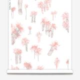 Partially unrolled wallpaper yardage in a playful palm tree print in shades of gray and pink on a white field.