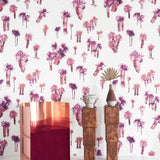 A modernist living tableau with a wall papered in a playful palm tree print in shades of red and purple on a white field.